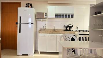 Una cocina compacta equipada con refrigerador, microondas y estufa a gas.