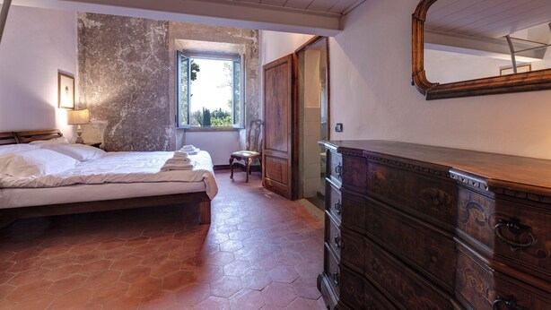 Una camera da letto con un letto, una cassettiera, una finestra e una porta.