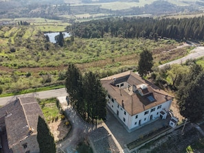 Un grand bâtiment doté de nombreuses fenêtres et d’un toit en pente, entouré de verdure et bordé d’un petit plan d’eau.