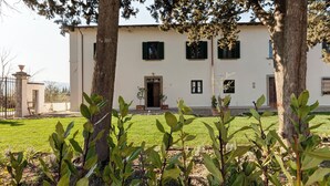 Un edificio con facciata simmetrica, un ingresso centrale e un prato ben curato in primo piano.