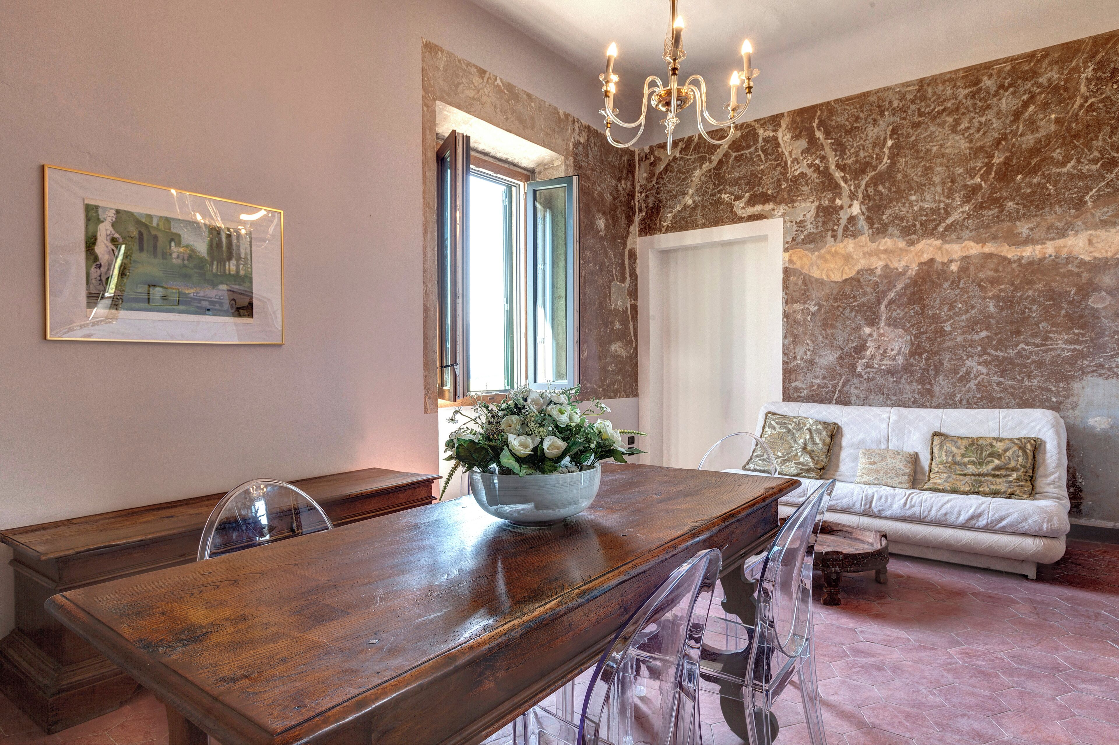 A dining area with a wooden table, chairs, and a vase of flowers.