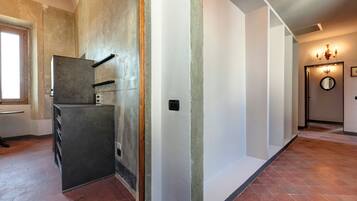 Un couloir avec un réfrigérateur, une porte dotée d’un miroir et un luminaire.