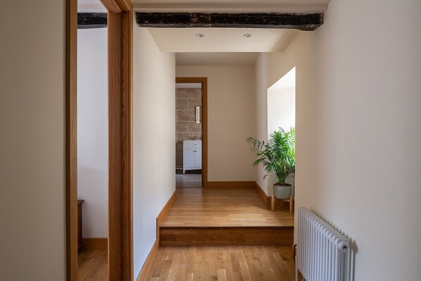 A hallway with wooden flooring, a radiator, and a potted plant.