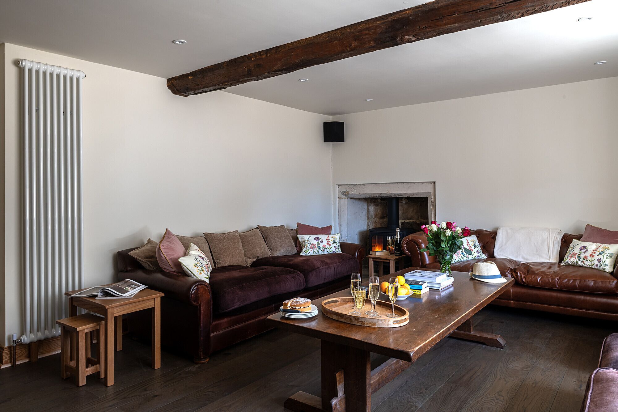 A cozy living room with a brown leather sofa, a wooden coffee table with a tray, and a fireplace.