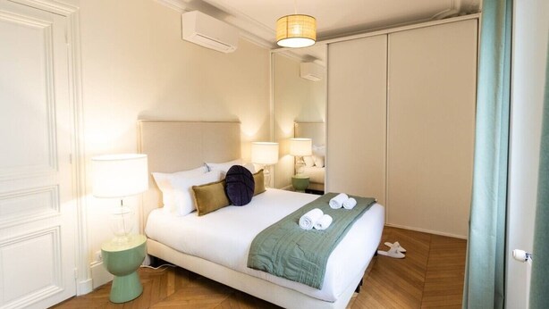 A hotel room with a bed, bedside lamps, a mirror, and a green throw blanket. - A2-8 people-4 bedrooms-Wagram-AC-Paris 8 (Paris)