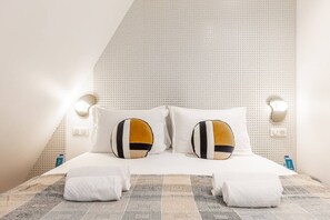 A neatly made bed with two pillows, a bedside table, and a wall-mounted light fixture. - B6D-2 people-Wagram-1 bedroom-Ternes-AC (Paris)