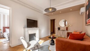 A modern living room with a fireplace, a sofa, a television, and a dining area. - B2G. 6 people—Champs-Élysées—Wagram—Arc de Triomphe—AC (Paris)