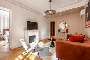 Uma sala de estar moderna com lareira, um sofá, uma televisão e um espaço de refeições.