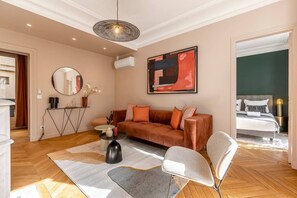 A modern living room with a sofa, a round mirror, a coffee table, and a painting on the wall. - B2G. 6 people—Champs-Élysées—Wagram—Arc de Triomphe—AC (Paris)