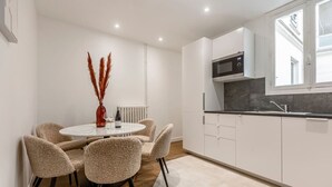 A modern kitchen with white cabinets, a microwave, and a window above the sink. - B2G. 6 people—Champs-Élysées—Wagram—Arc de Triomphe—AC (Paris)