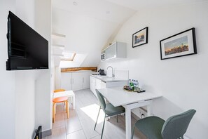 A modern kitchen with white cabinets, a dining table, and two chairs. - Palais Royal – Louvre Museum – Central Studio (Paris)