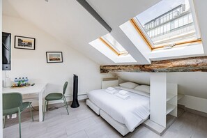 A room with a bunk bed, a desk with a chair, a guitar, and a skylight. - Palais Royal – Louvre Museum – Central Studio (Paris)