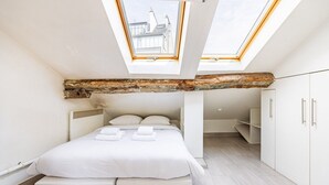 Et moderne soveværelse med ovenlys, en seng med puder og et loft med træbjælker.