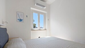 Ein Schlafzimmer mit Bett, Fenster und Klimaanlage.