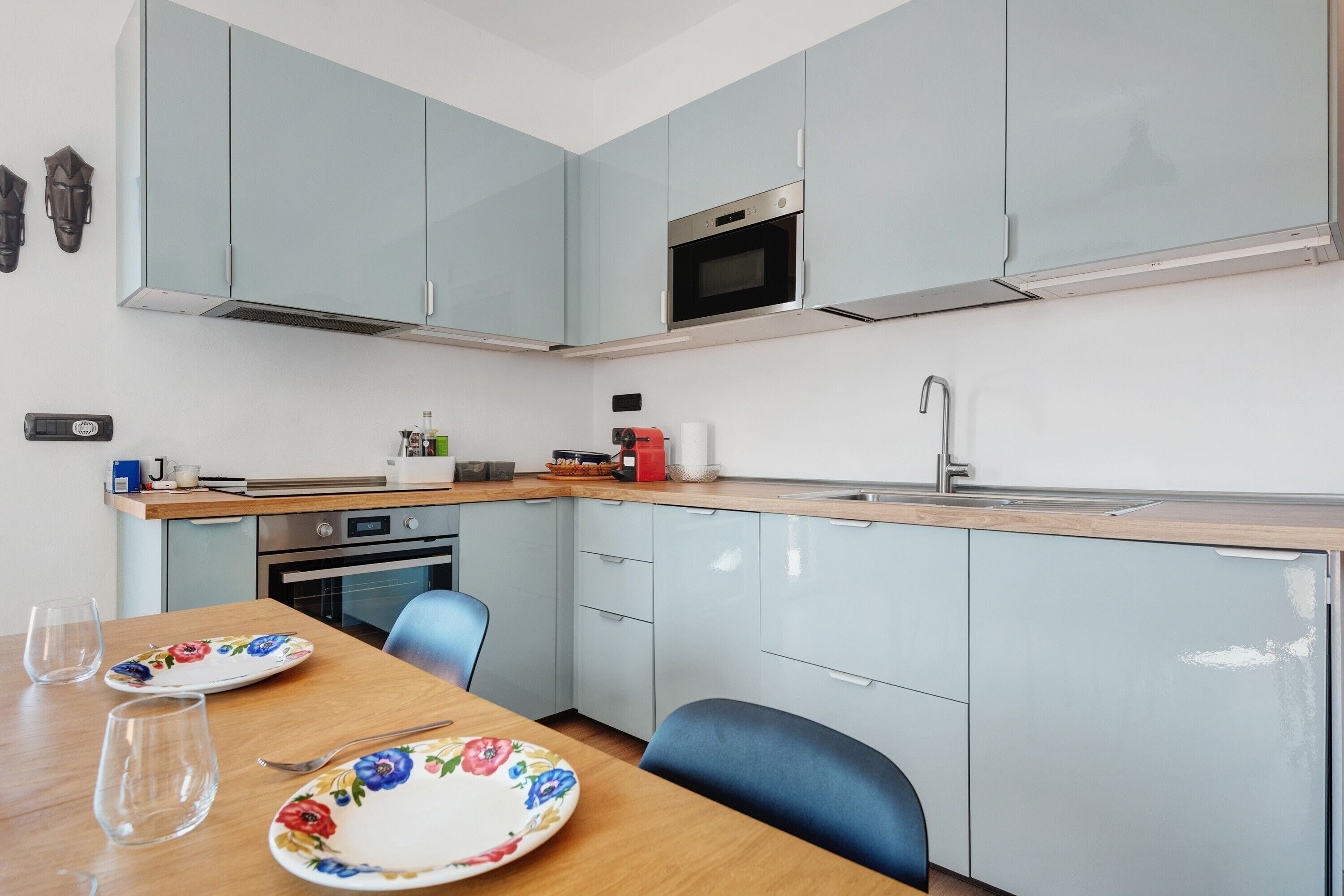 Uma cozinha compacta com armários azul-claros, um micro-ondas, um fogão e uma pia.