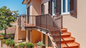 Ein zweistöckiges Gebäude mit einem Balkon, einer Treppe und einem Ziegeldach.