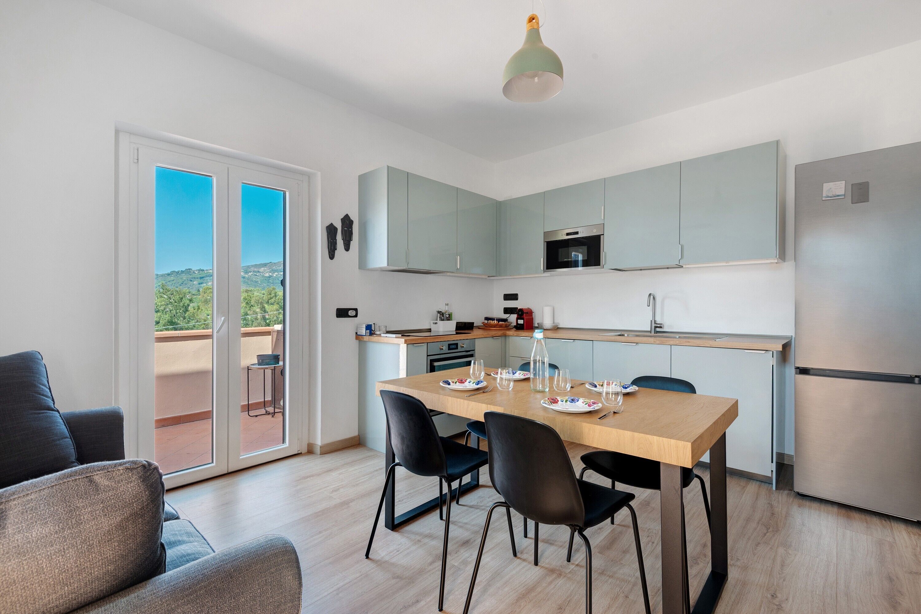 Une cuisine moderne avec un coin repas, un balcon offrant une vue agréable et un luminaire au plafond.