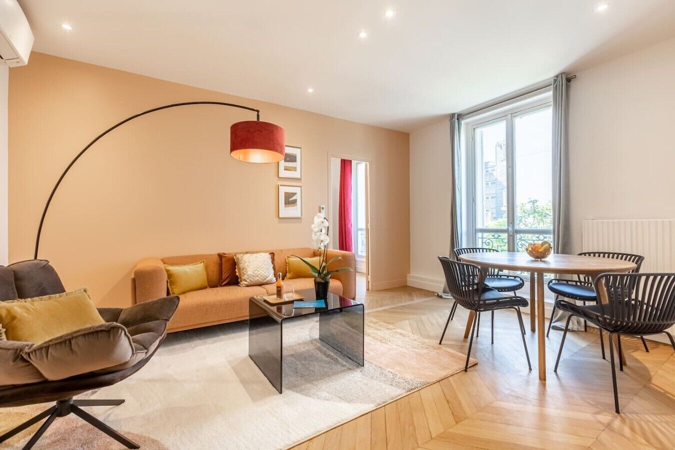 A modern living room with a sofa, coffee table, and dining area with chairs.