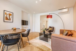 A modern living room with a round dining table, black chairs, a glass coffee table, a red pendant light, a brown sofa, and a TV mounted on the wall. - B3D. 4 people—Champs-Élysées—Wagram—Arc de Triomphe—AC (Paris)