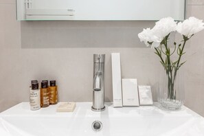A bathroom sink with toiletries, a mirror, and a vase with flowers. - B3D. 4 people—Champs-Élysées—Wagram—Arc de Triomphe—AC (Paris)