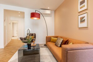 A modern living room with a sofa, a coffee table, and a red pendant light. - B3D. 4 people—Champs-Élysées—Wagram—Arc de Triomphe—AC (Paris)