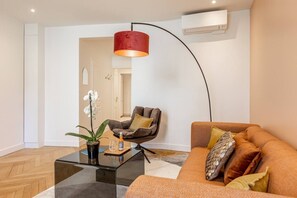 A modern living room with a sofa, a coffee table, a floor lamp, and a potted orchid. - B3D. 4 people—Champs-Élysées—Wagram—Arc de Triomphe—AC (Paris)