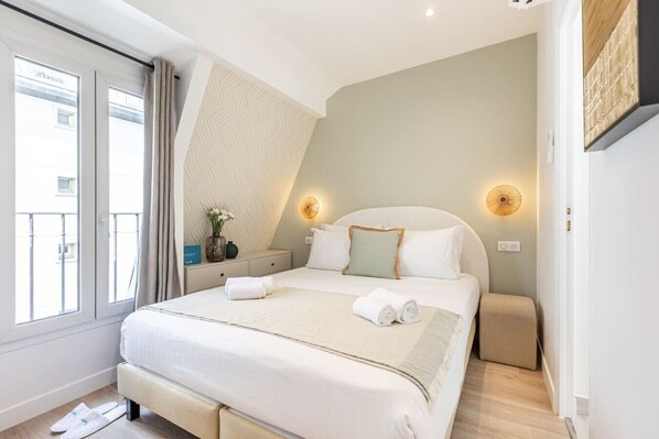 A hotel room with a bed, bedside table, and a view of the outside. - B6G - 2people - Wagram - Studio - Ternes - AC (Paris)