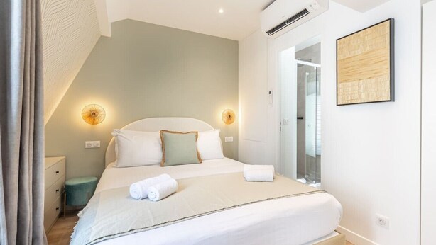 A hotel room with a bed, bedside tables, a mirror, and a wall-mounted air conditioner. - B6G - 2people - Wagram - Studio - Ternes - AC (Paris)