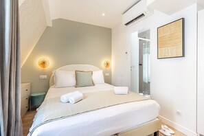 A hotel room with a bed, bedside tables, a mirror, and a wall-mounted air conditioner. - B6G - 2people - Wagram - Studio - Ternes - AC (Paris)