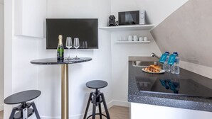 A modern kitchen with a black countertop, a wine bottle, and glasses on a small round table. - B6G - 2people - Wagram - Studio - Ternes - AC (Paris)