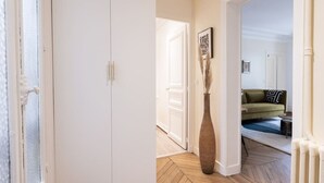A hallway with a white door, a vase with pampas grass, and a green sofa in the background. - B1G. 4 people—Champs-Élysées—Wagram—Arc de Triomphe—AC (Paris)