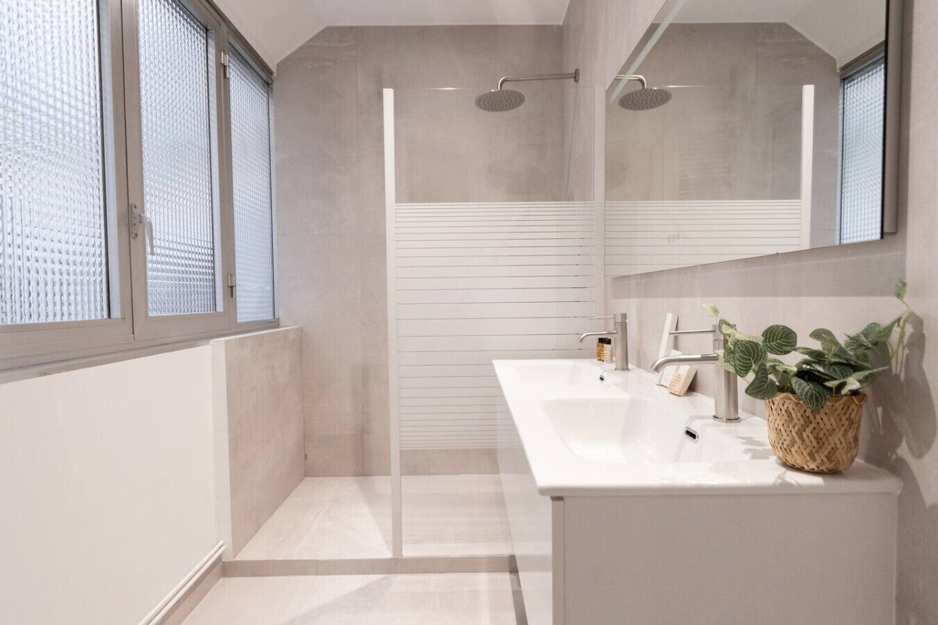 Ein modernes Badezimmer mit Dusche, Waschbecken und Spiegel.
