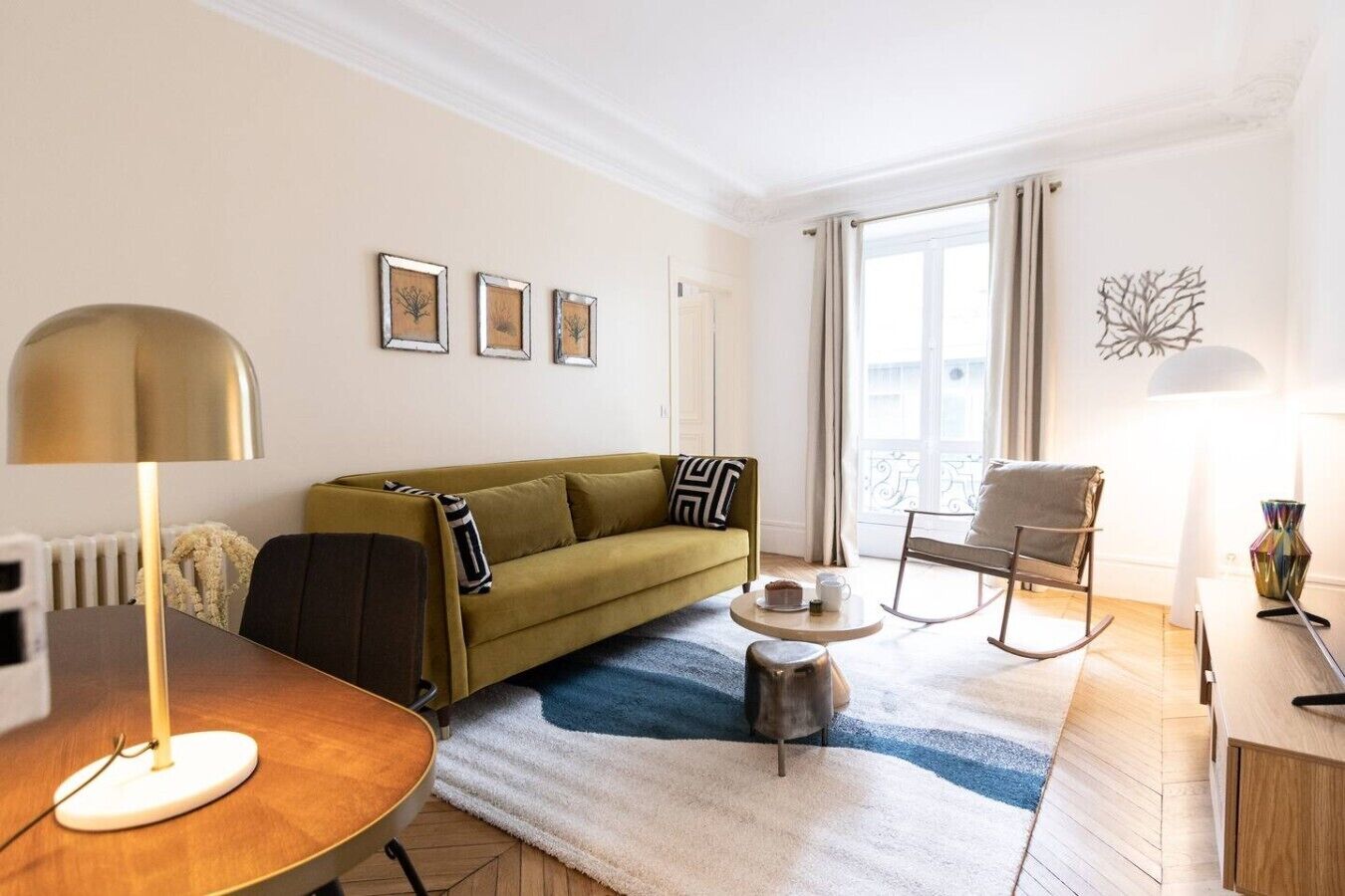A modern living room with a sofa, a coffee table, a rocking chair, and a lamp.