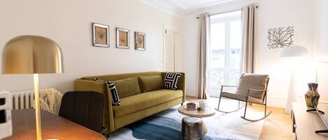 A modern living room with a sofa, a coffee table, a rocking chair, and a lamp.