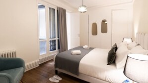 A hotel room with a bed, a chair, a window with curtains, a radiator, and a lamp. - B1G. 4 people—Champs-Élysées—Wagram—Arc de Triomphe—AC (Paris)