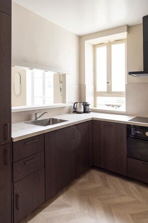 Eine moderne Küche mit dunklen Holzausführungen, einer Edelstahlspüle und einem Fenster für natürliches Licht.