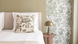 Un dormitorio con cama, mesita de noche y un papel tapiz floral.