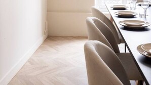 Un comedor con una mesa larga dispuesta para cuatro, un espejo en la pared y una ventana con vistas al exterior.