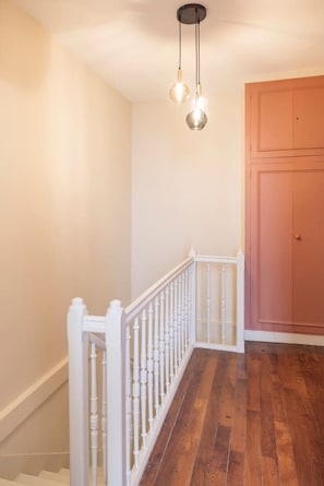 Eine Treppe mit weißen Spindeln führt zu einer Zwischenebene, ein Holzboden und eine Tür mit schlichtem Design sind zu sehen.