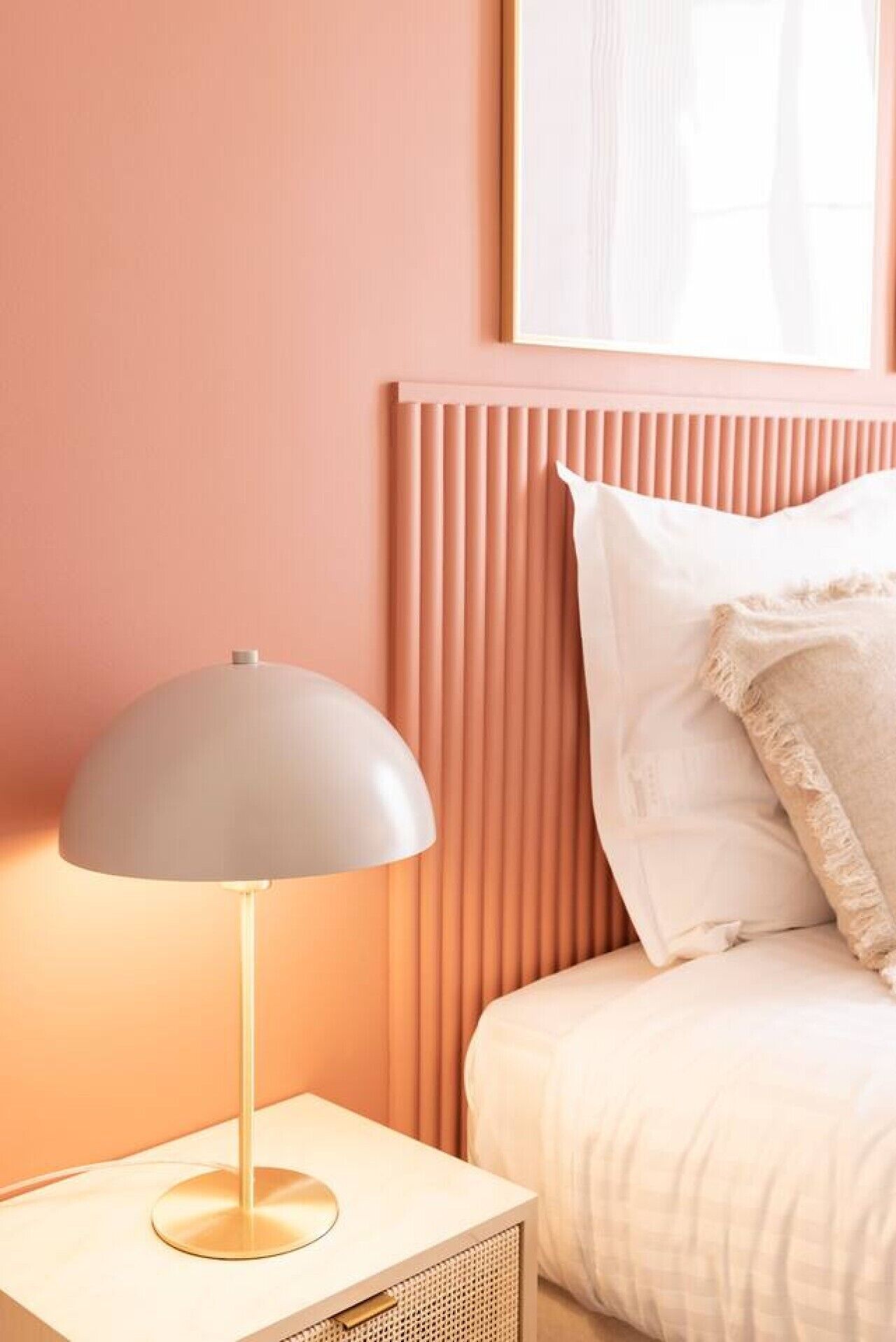 Un dormitorio con cama, lámpara de noche y cabecera.