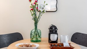 A table with a bowl of snacks, a coffee maker, a mug, and a vase with flowers. - B2D-2 people-Wagram-1 bedroom-Ternes-AC (Paris)