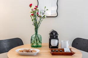 A table with a bowl of snacks, a coffee maker, a mug, and a vase with flowers. - B2D-2 people-Wagram-1 bedroom-Ternes-AC (Paris)