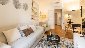 A modern living room with a sofa, a coffee table, and a dining area with a table and chairs. - B2D-2 people-Wagram-1 bedroom-Ternes-AC (Paris)