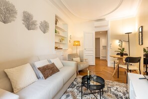 A modern living room with a sofa, a coffee table, and a dining area with a table and chairs. - B2D-2 people-Wagram-1 bedroom-Ternes-AC (Paris)