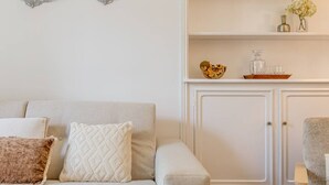 A living room with a sofa, two cushions, a cabinet, and a small table with decorative items. - B2D-2 people-Wagram-1 bedroom-Ternes-AC (Paris)