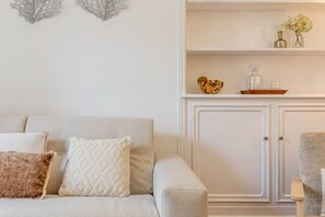 A living room with a sofa, two cushions, a cabinet, and a small table with decorative items. - B2D-2 people-Wagram-1 bedroom-Ternes-AC (Paris)