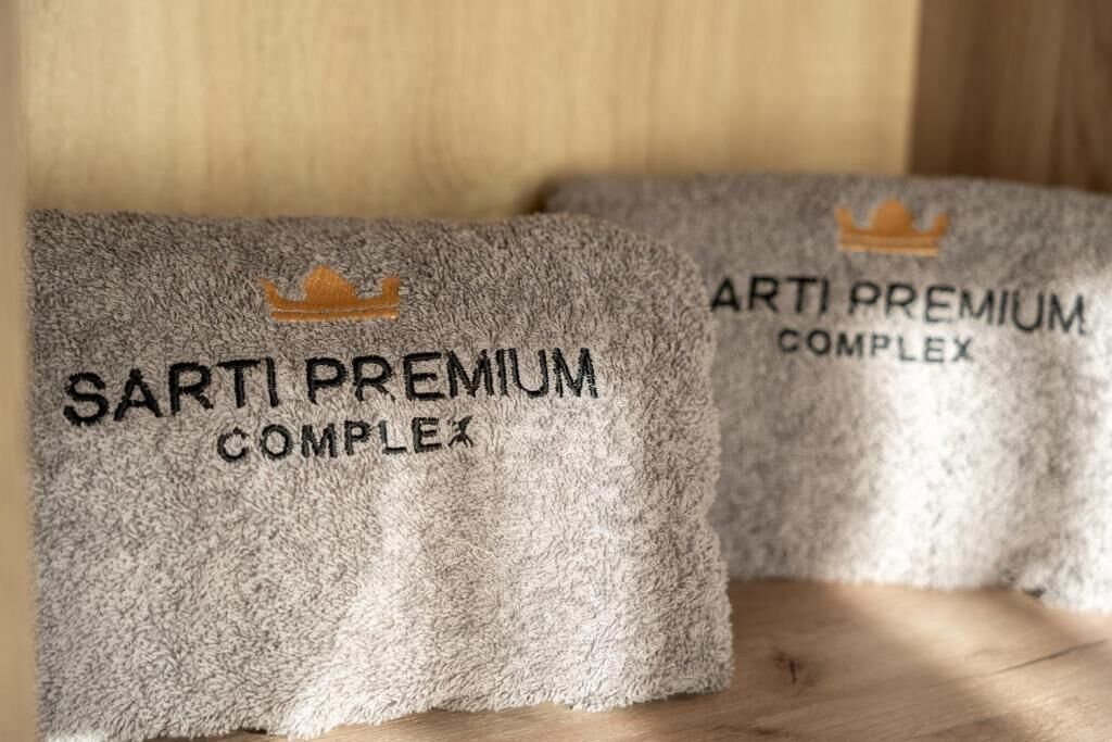 Two towels with 'SARTI PREMIUM COMPLEX' text and a crown symbol.
