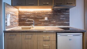 A modern kitchen with wooden cabinets, a built-in dishwasher, and a stone backsplash. - SARTI PREMIUM LUXURY SUITES  (SITHONIA)