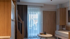 A modern interior with a staircase, a round table with books and a vase, and a sofa. - SARTI PREMIUM LUXURY SUITES  (SITHONIA)