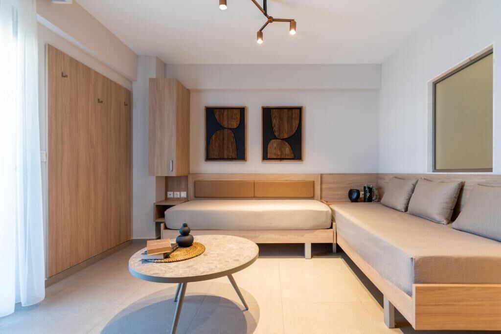 A modern bedroom with a bed, a sofa, a bedside table, and artwork on the wall.